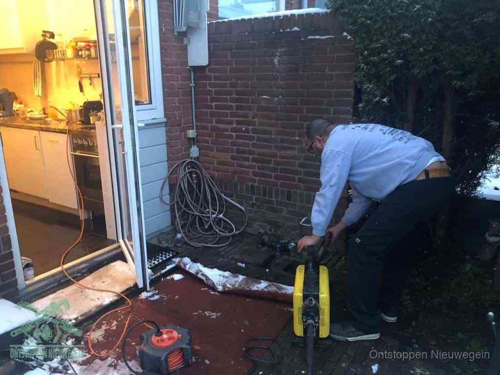 Een monteur werkt buiten bij een open riool-/grondput met een elektrische ontstoppingsmachine om een verborgen afvoerprobleem op te sporen in Nieuwegein
