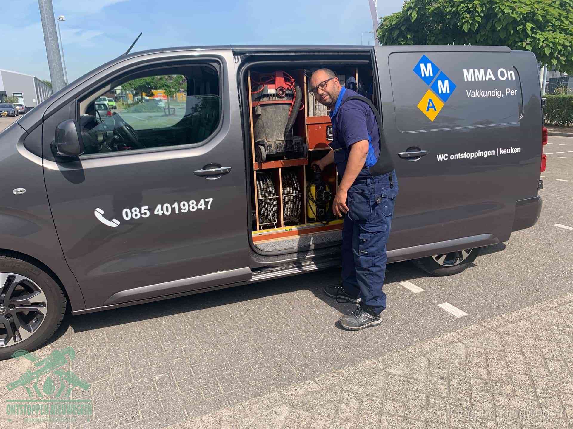 Een monteur bij de open schuifdeur van zijn bedrijfsbus op een parkeerplaats, klaar om de oorzaak van terugkerende afvoerverstoppingen aan te pakken in Nieuwegein