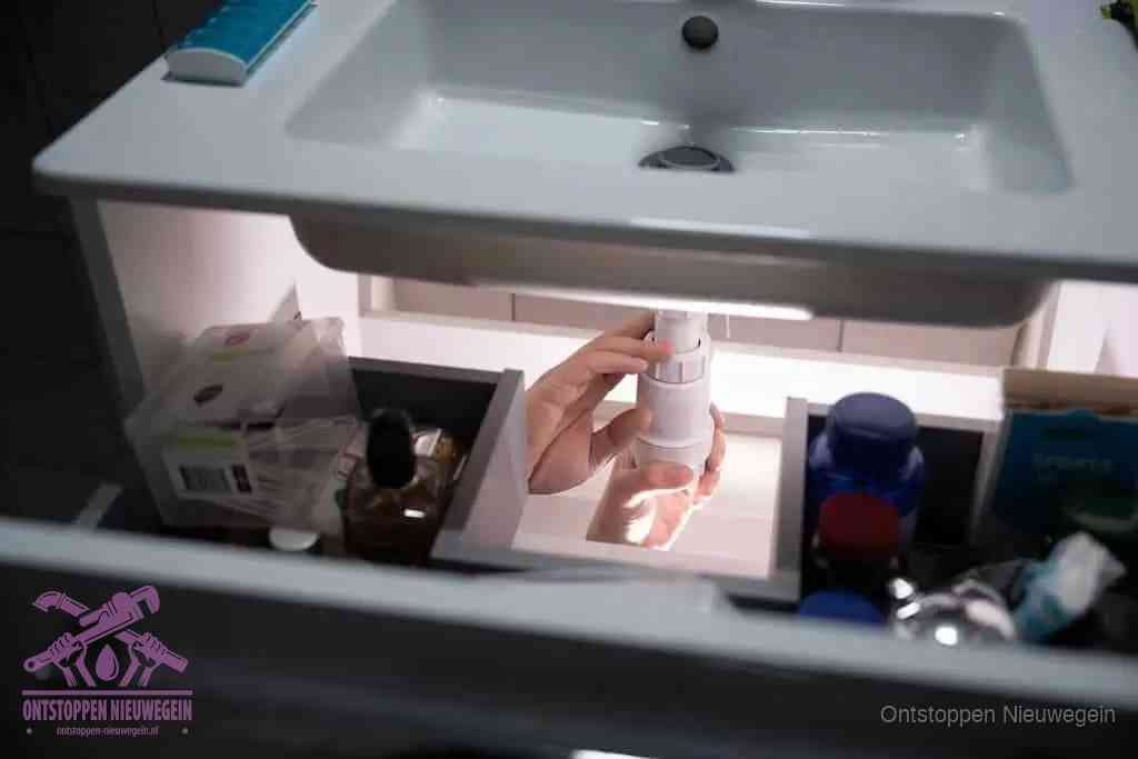 Een pompfles met zeep boven een wastafel in de toiletruimte, de warm water en afwasmiddel-methode om de wc te ontstoppen in Nieuwegein