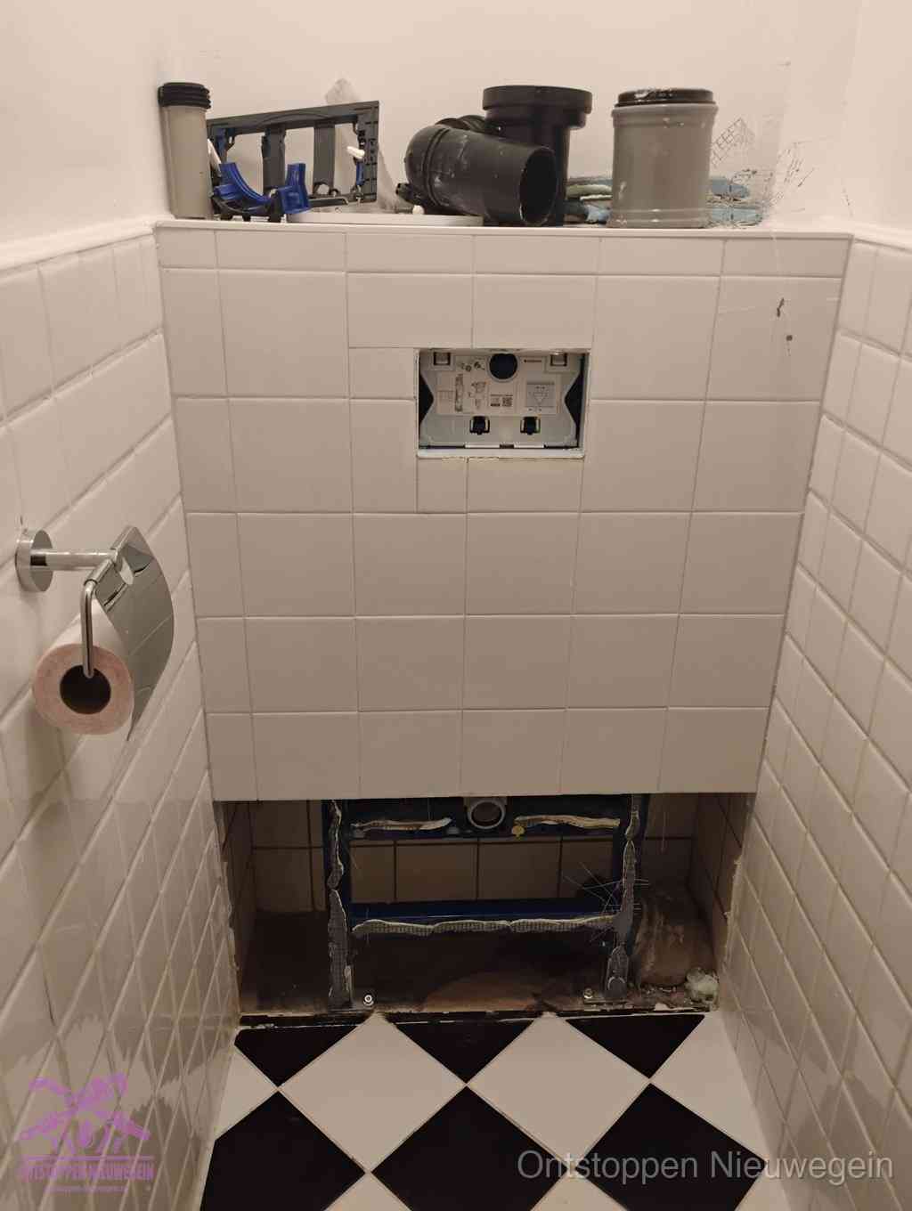 Een toiletruimte waar het hangtoilet en de inbouwreservoir-onderdelen zijn vrijgelegd voor onderhoud, periodiek nazicht voorkomt een wc-verstopping in Nieuwegein
