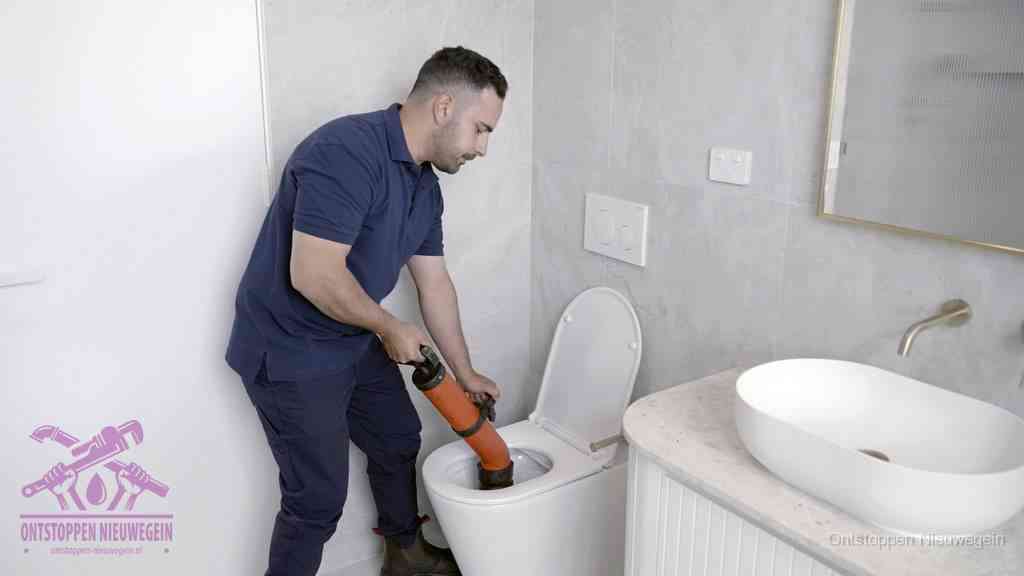 Een man gebruikt een handmatige luchtdruk-ontstopper in een modern betegeld toilet om zelf de wc te ontstoppen in Nieuwegein